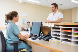 Nurse and patient conversing at reception desk in hospital